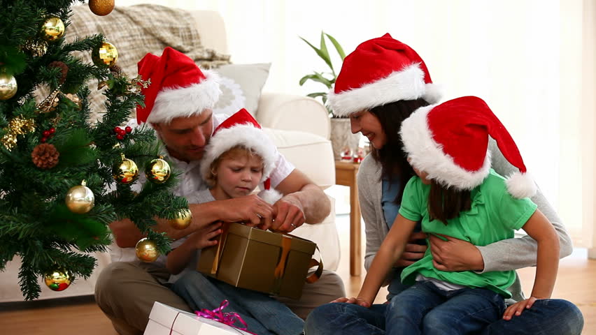 Cute family opening Christmas present sitting on the floor in the living-room