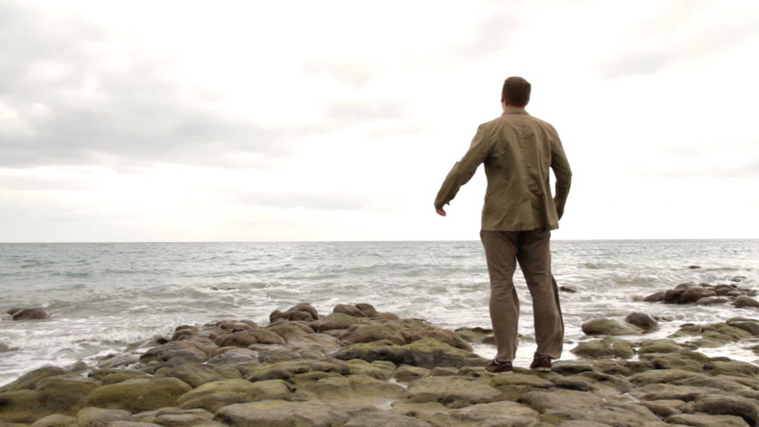 Man at the beach rising hands to the sky