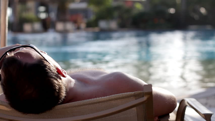Young man lying on sunbed at swimming pool