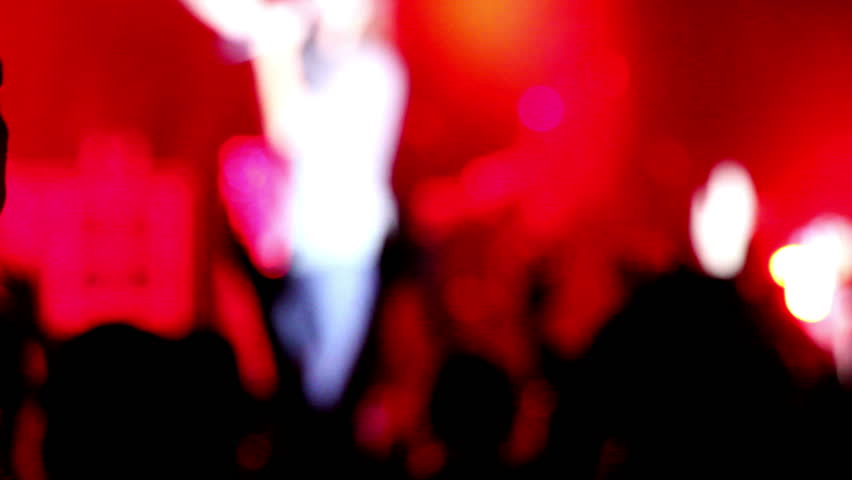 Anonymous crowd waving hands in the air at rock concert.
