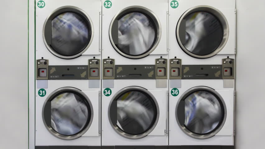 six large washing machines in public laundry room with rotating drums
