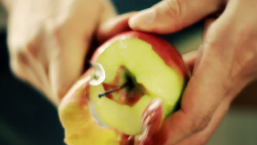 Male hands peeling red apple, close up