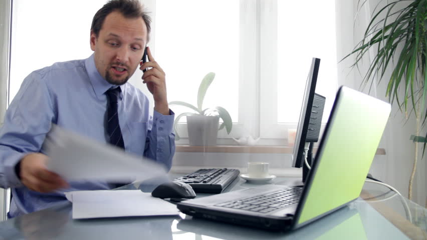 Angry businessman in the office talking on mobile phone