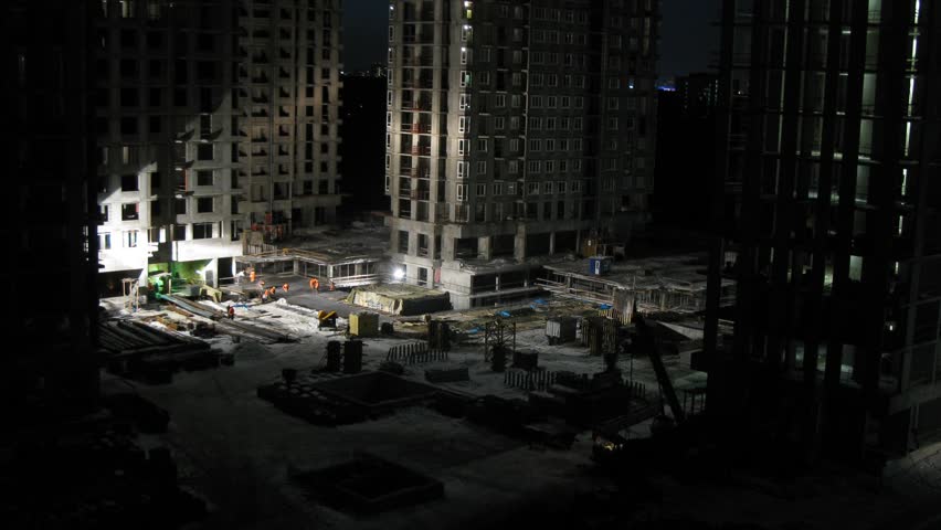 Builders work on construction site at night, time lapse