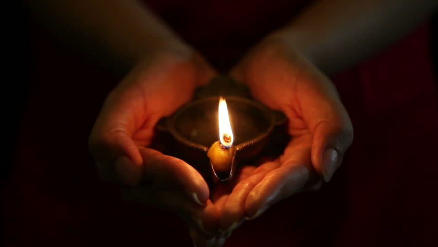 hands holding a single brass oil lamp