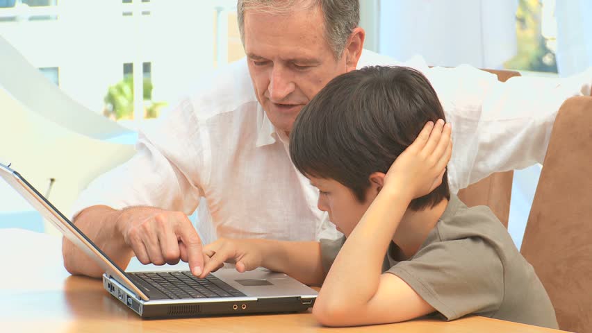 A grandfather giving some explanations to his grandson about a laptop