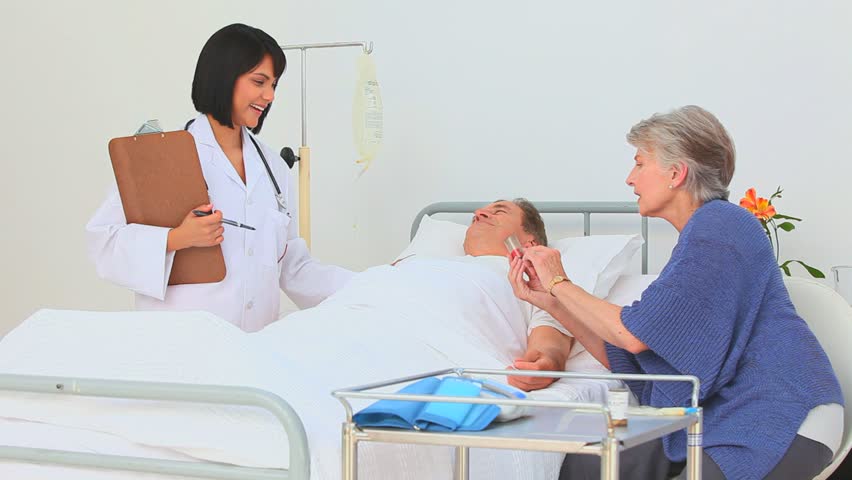 Nurse ginving explanations about pills to the wife's patient at the hospital