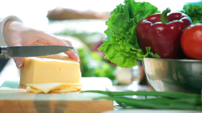 women hands slicing the cheese on the kitchen table