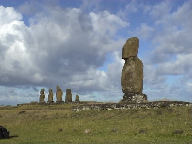 Person walking and standing next to ancient Moai statues on Easter Island, in the South Pacific.