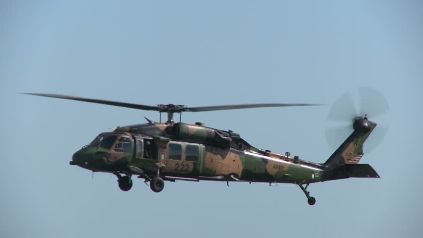 A blackhawk military helicopter hovers over an airfield as it comes under attack