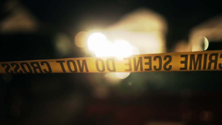 Crime scene tape blowing in a slight breeze around a real crime scene.
