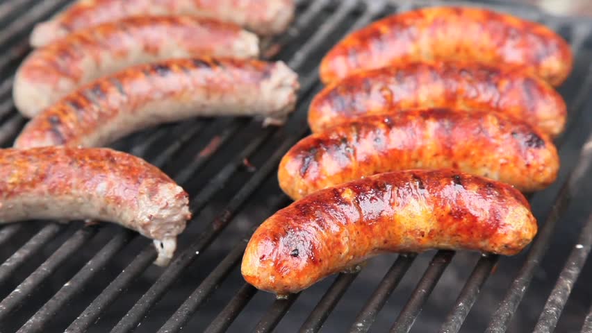 Bratwurst sausages cooking on a wood barbecue.