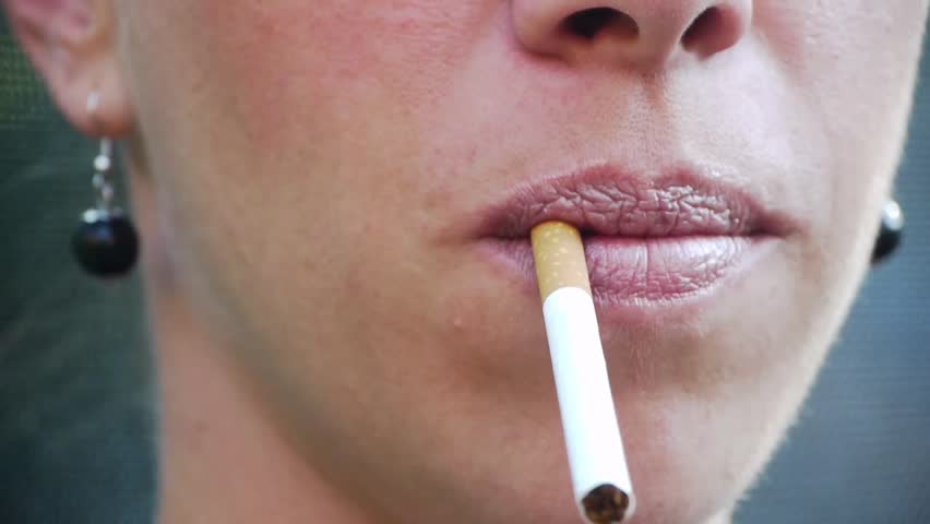 A woman with great lips lights a cigarette and has an intensive smoke