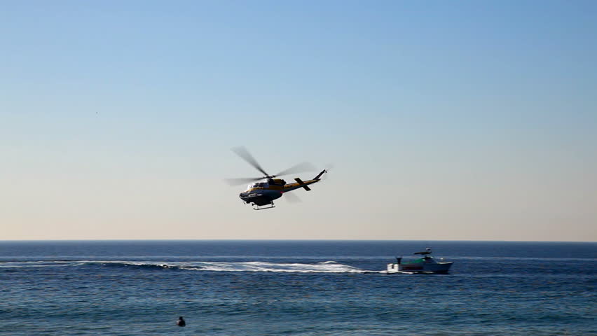 The camera tracks a helicopter as flies low over the Pacific Ocean.