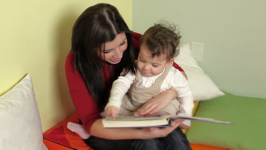 Baby girls listening to fairy tale in kindergarten and educator reading book