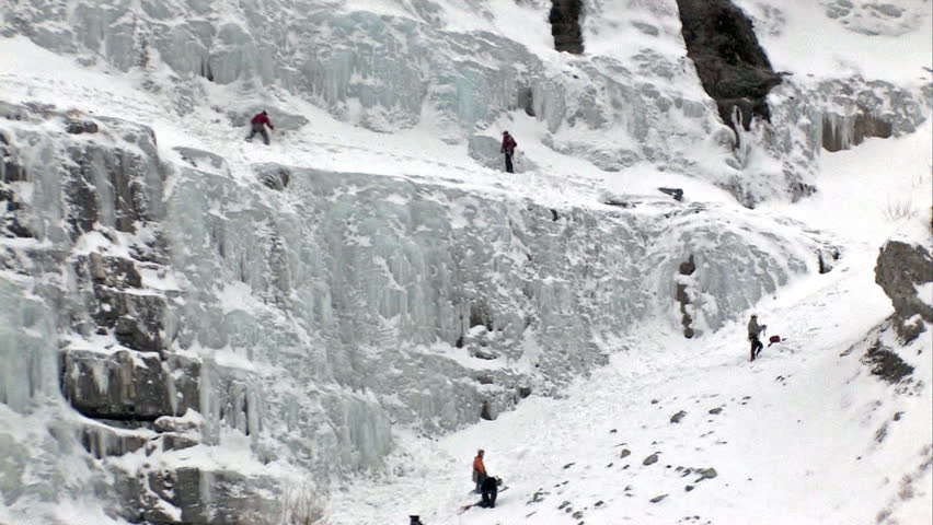 Video of ice climbers climbing ice flow at Bridal Vale Falls in central Utah. Pan up Steep rock ledges with frozen waterfall. Wasatch Mountain range part of the Rocky Mountains. 