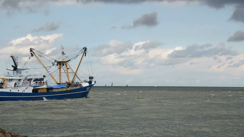 Fishing trawler sails into open sea from Scheveningen harbor, Holland