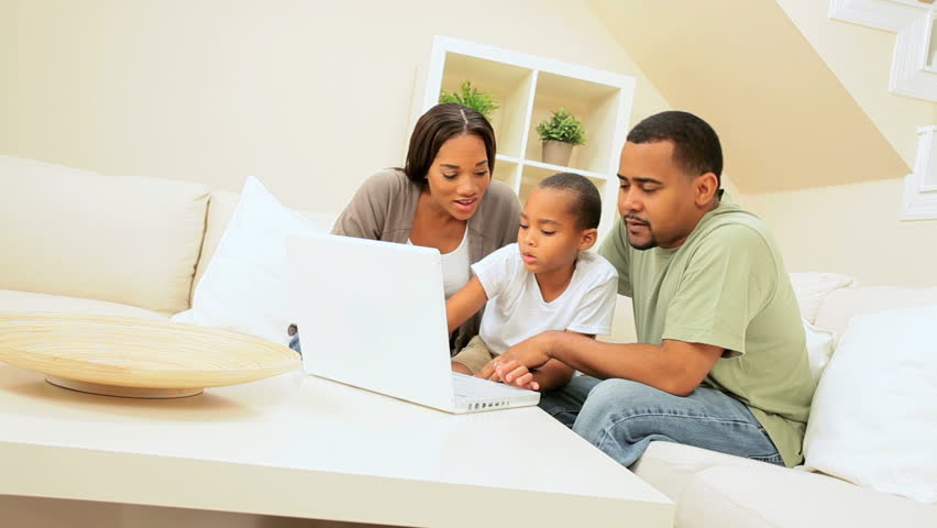 Young african-american boy showing his parents some computer programs on his laptop
