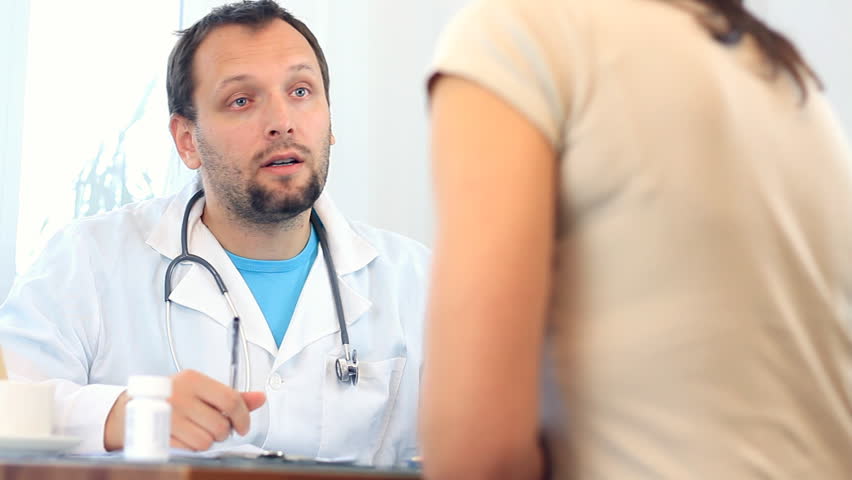 Male doctor writing rx prescription for female patient