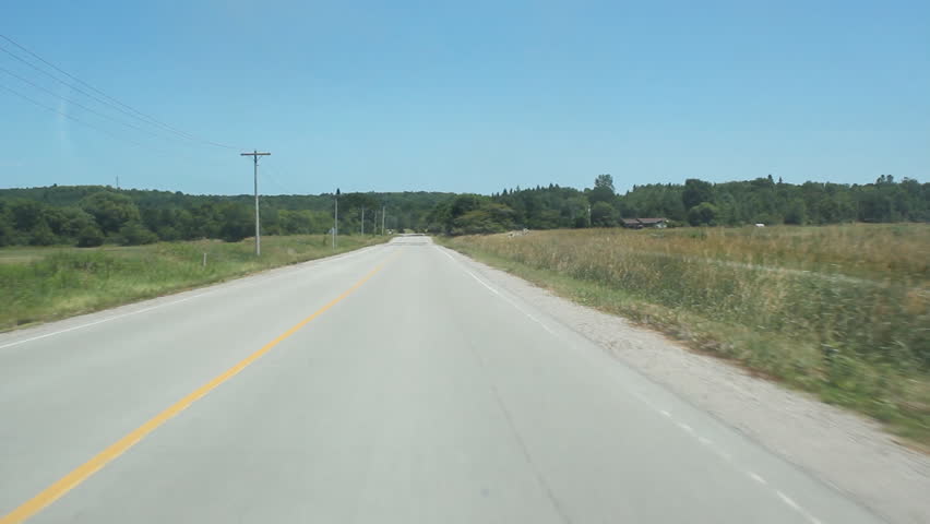 Rural road. Driving on a quiet rural road in the summer. Slight reflection from dash on right side of windshield. Ontario, Canada. 