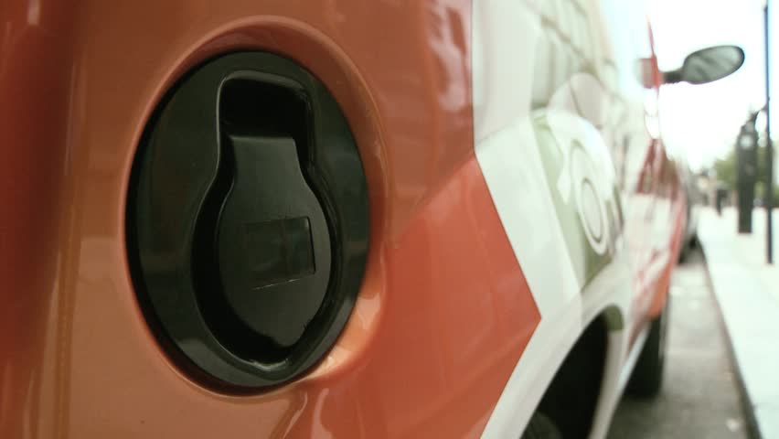 Close up plugging in power cord to an electric car  