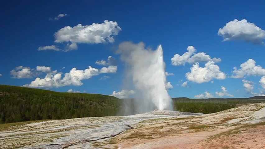 Old Faithful Geyser erupts on a beautiful evening in Yellowstone National Park - USA