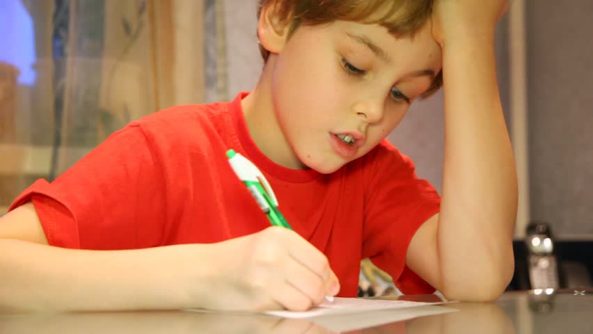 Close-up of serious boy very attentively writes something