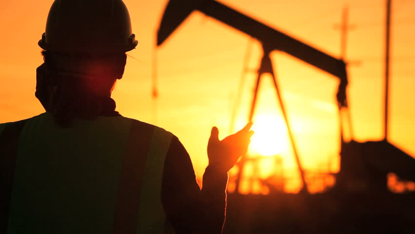 Female engineer communicating by cell phone from crude oil drilling site