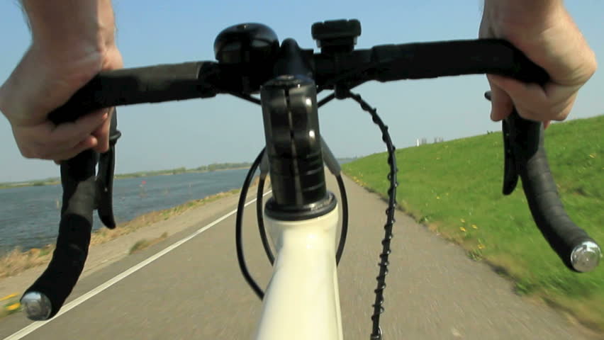 View on a steering wheel of a racing bike riding on a bicycle path in the country.