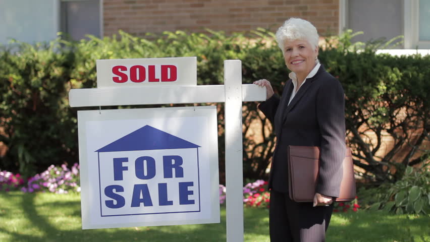 Real estate agent in front of a sold house