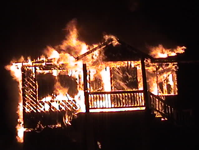 Structure fire at night with falling debris and the front porch roof collapse.