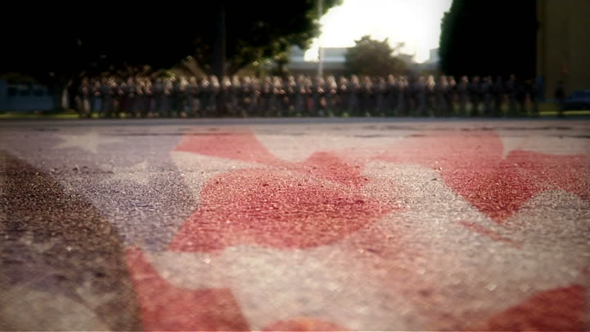 Very low shot of American flag painted on concrete, Marines out of focus marching in background