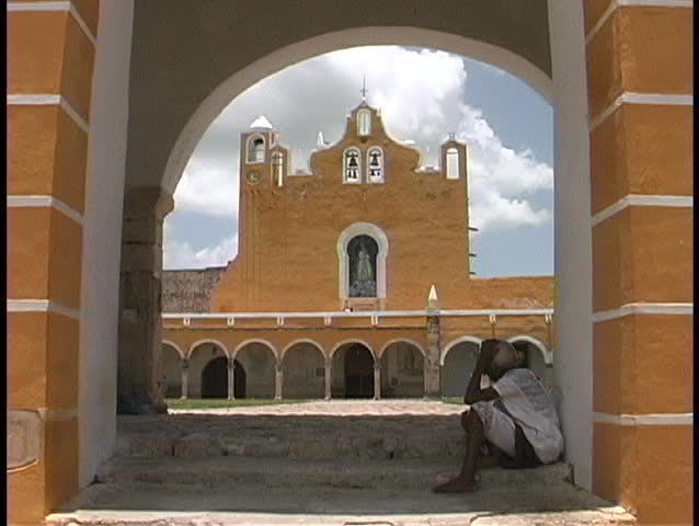 A terracotta colored church is seen across the courtyard of a convent in Izamal, Mexico.