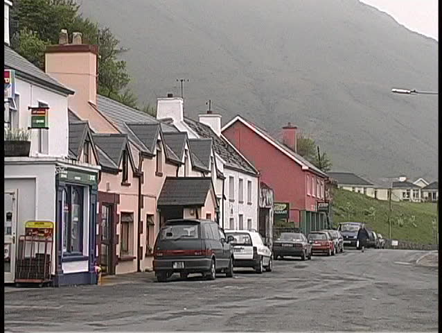 Woman in raincoat strolls through the mist  in a small Irish village.