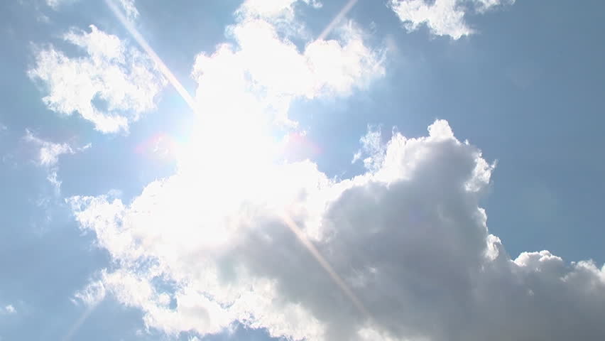 Sunny weather. The clouds float across the blue sky. cumulus clouds and permutations. The sun hides behind clouds.
