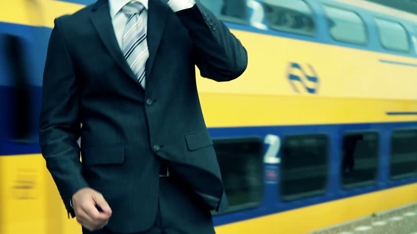 Business male answering phone at train station