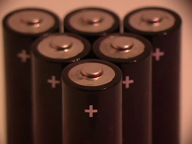 Pan left to right to  reveal six batteries for a portable electronic device.