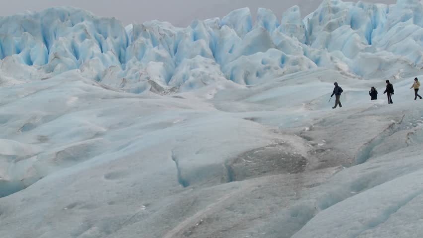 An expedition moves across a glacier landscape.