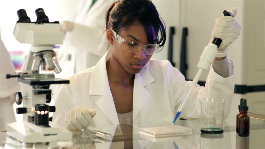 A pretty African American lab tech or chemistry student using a macro-pipette to dispense precise amounts of sample into a specially designed container.