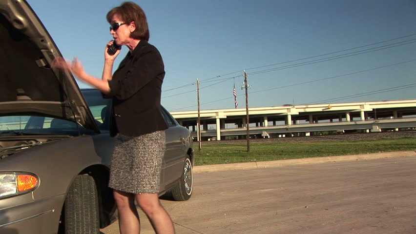 An attractive womanÃ¢â¬â¢s car breaks down she uses her cell phone to call for help.