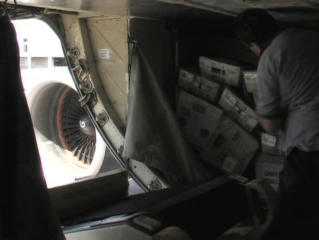 LOS ANGELES, CA - CIRCA 2006: An employee grabs boxes from a conveyor belt and stacks them into the cargo hold of a plane circa 2006 in Los Angeles.
