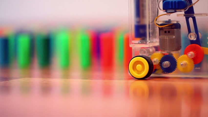 Toy machine moves and put colored domino blocks behind 