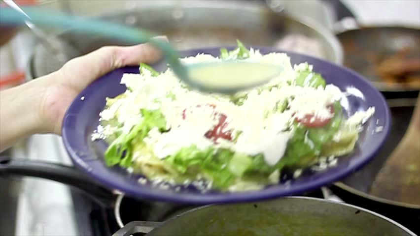 decorating the plate with green sauce over the enchiladas with legumes