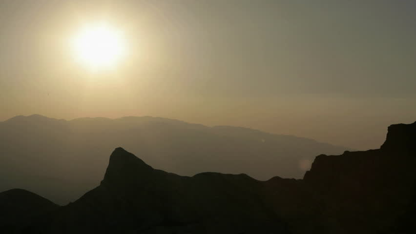 Haze hangs in a valley under an orange sky