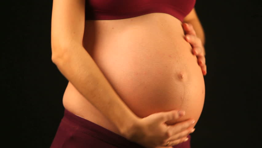 close up of a young mother to be rubbing her pregnant abdomen
