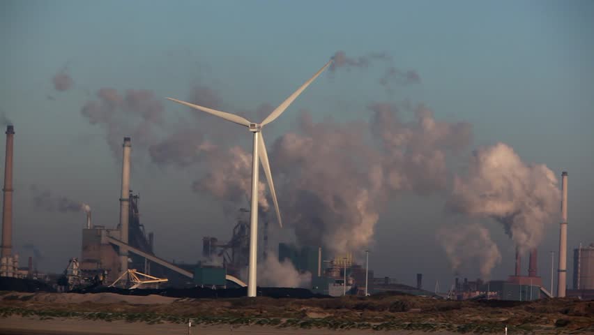 Wind turbine with big smokestacks in the background