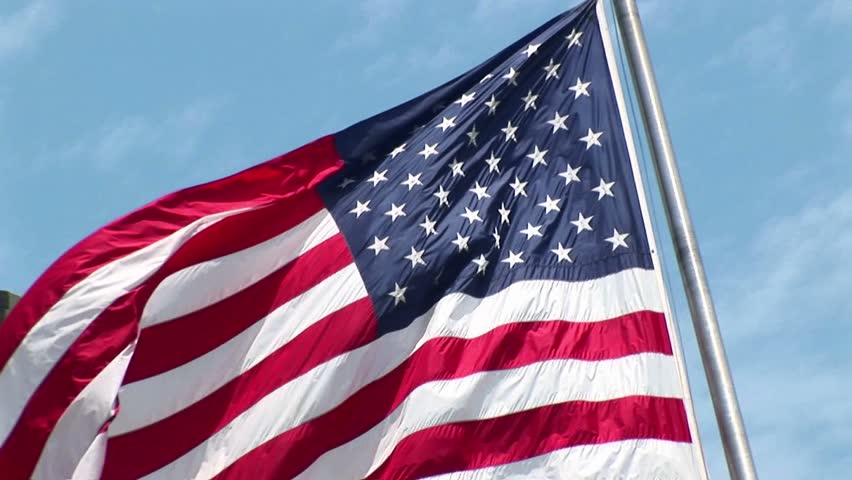 NEW YORK - CIRCA 2005: The camera pans-left across a rippling American flag, revealing the Statue of Liberty in the background in New York, NY circa 2005