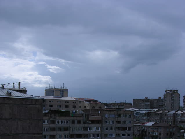 Sky with moving clouds over city buildings. Time lapse