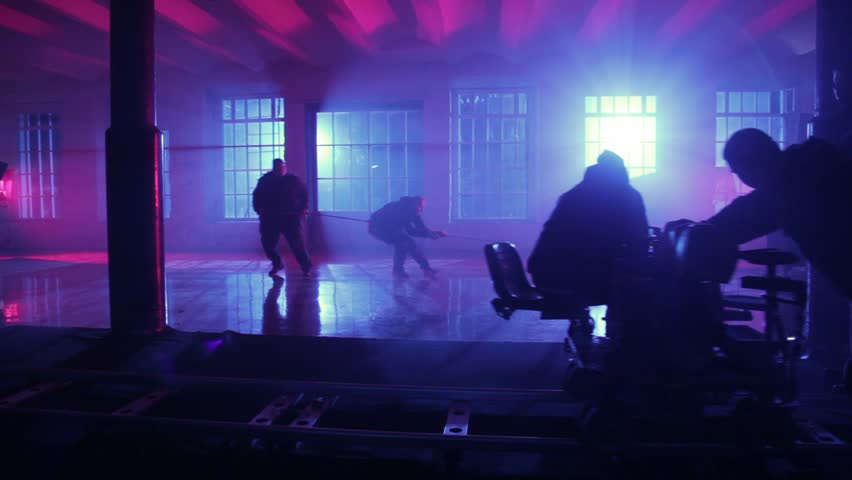 operator with videocamera moving on rail cart shooting, man in armchair which drag ropes on floor