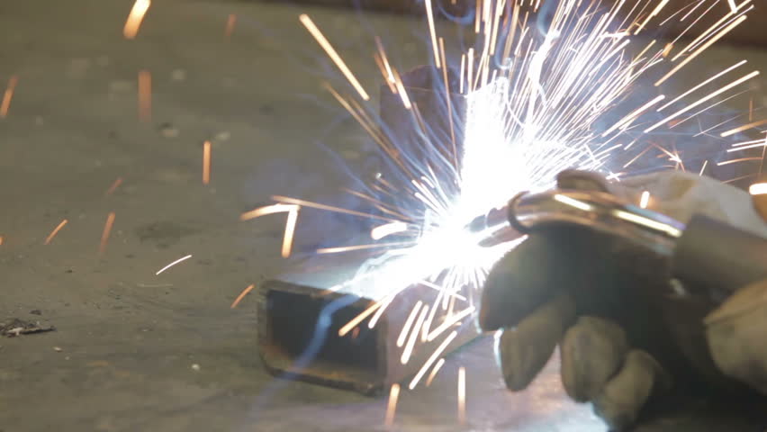 Welding two parts of heavy rusted steel on a work table. Small business helps keep employment high. Manual labor and skilled metal worker.